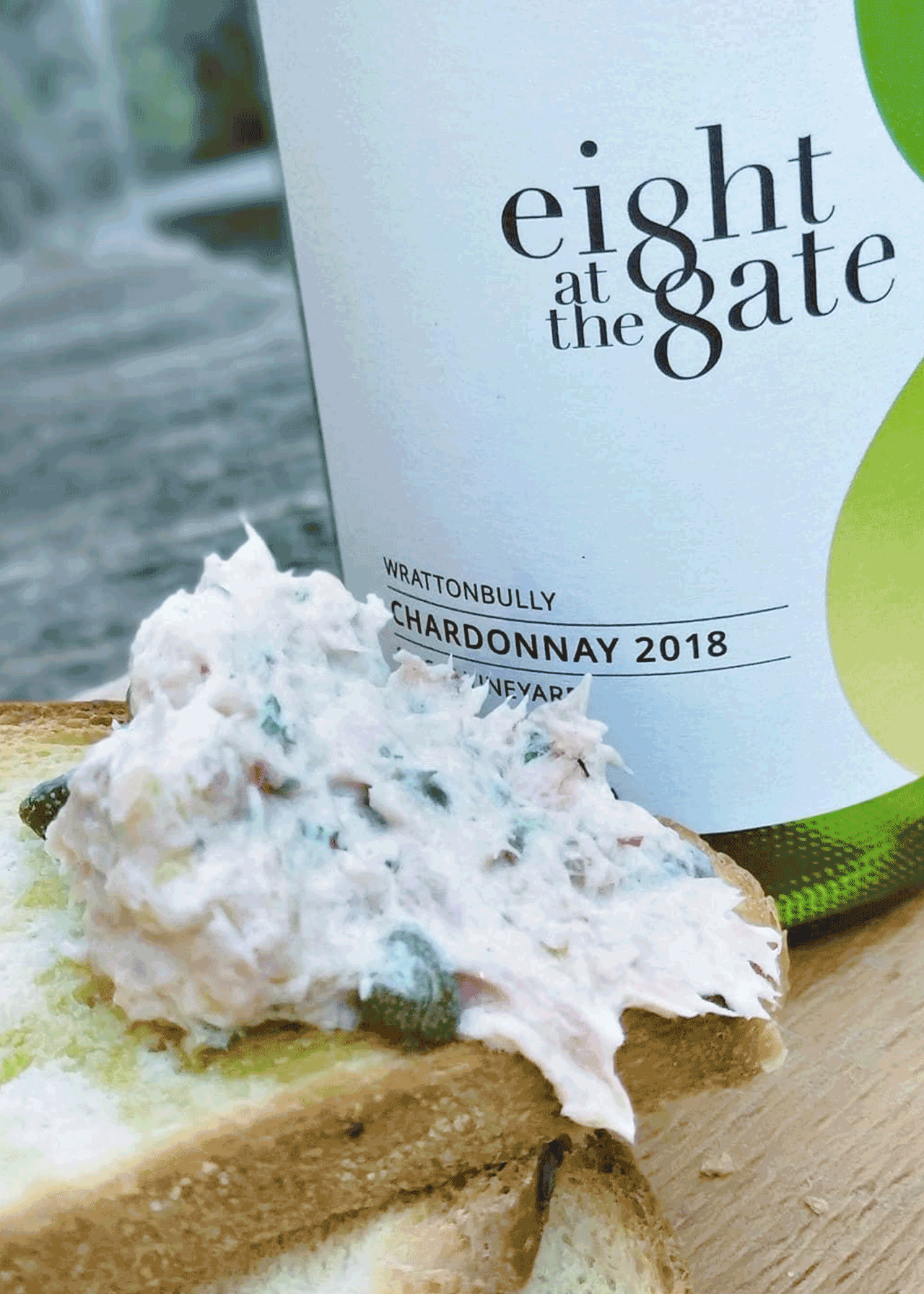 Close up shot of Eight at the Gate 2018 Chardonnay front label with food placed in front.